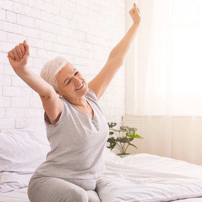 Mature woman stretching after night of restful sleep